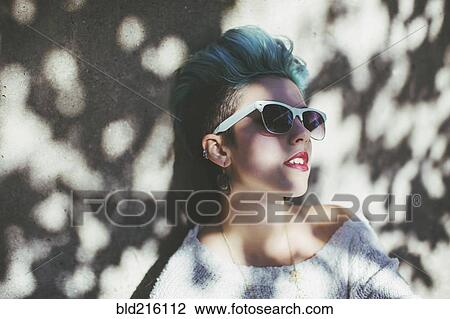 Stock Image - Stylish Caucasian woman wearing sunglasses in shade. Fotosearch