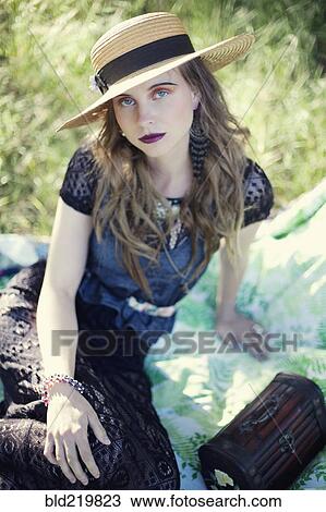Stock Image - Stylish woman sitting on blanket. Fotosearch