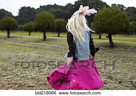 Stock Photograph - Stylish woman walking in rural field. Fotosearch