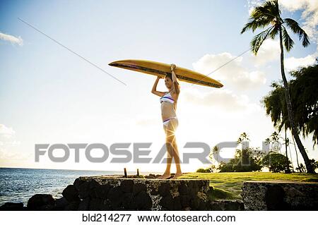Surfer holding surfboard over her head near ocean View Large Photo Image Stock Photo - Surfer holding surfboard over her head near ocean. Fotosearch