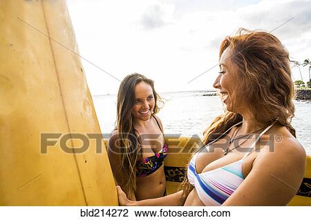 Stock Image - Surfers carrying surfboards near beach. Fotosearch