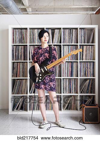 Taiwanese woman playing electric guitar near record collection View Large Photo Image Picture - Taiwanese woman playing electric guitar near record collection. Fotosearch