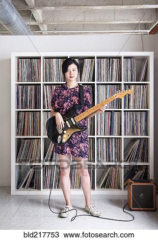 Taiwanese woman playing electric guitar near record collection View Large Photo Image Stock Image - Taiwanese woman playing electric guitar near record collection. Fotosearch