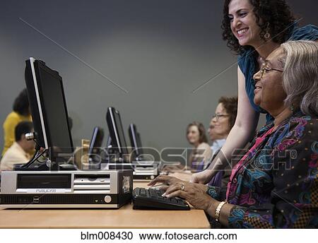 Teacher helping students on computers in computer lab View Large Photo Image Stock Image - Teacher helping students on computers in computer lab. Fotosearch