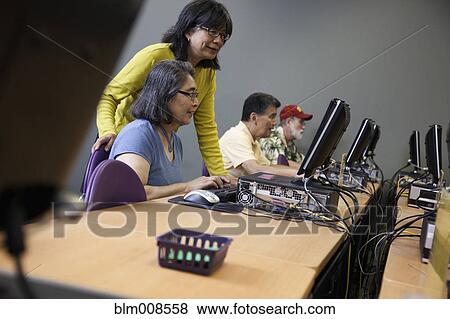 Stock Photo - Teacher helping students on computers in computer lab. Fotosearch