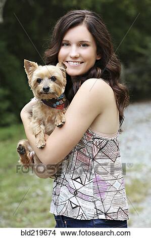Picture - Teenage girl carrying puppy in rural field. Fotosearch