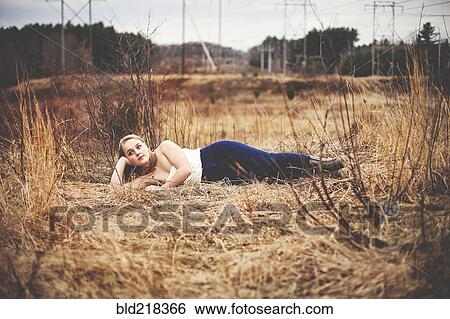 Teenage girl laying in tall grass in park View Large Photo Image Stock Photograph - Teenage girl laying in tall grass in park. Fotosearch