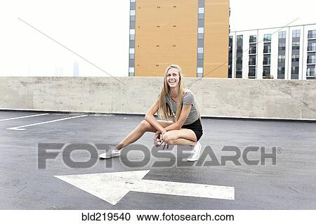 Stock Image - Teenage girl posing on urban rooftop parking lot. Fotosearch