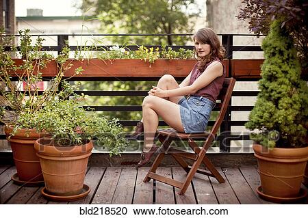 Stock Image - Teenage girl sitting on urban rooftop. Fotosearch