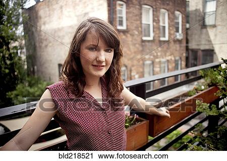 Stock Image - Teenage girl standing on urban rooftop. Fotosearch