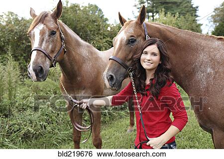 Stock Photograph - Teenage girl walking horses in rural field. Fotosearch