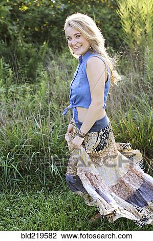 Stock Image - Teenage girl walking in tall grass. Fotosearch