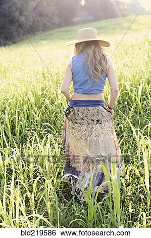 Stock Photograph - Teenage girl walking in tall grass. Fotosearch