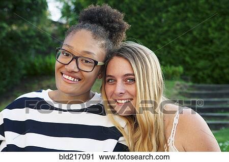 Stock Image - Teenage girls hugging in park. Fotosearch