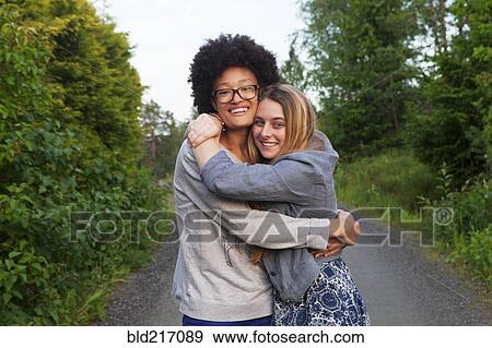 Teenage girls hugging on dirt path View Large Photo Image Stock Photo - Teenage girls hugging on dirt path. Fotosearch