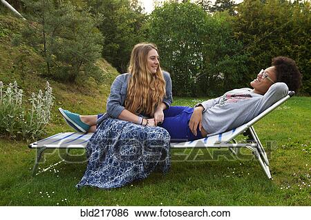 Teenage girls relaxing on lawn chair View Large Photo Image Stock Photograph - Teenage girls relaxing on lawn chair. Fotosearch