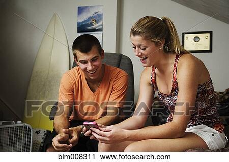 Stock Image - Teenagers looking at cell phone together. Fotosearch