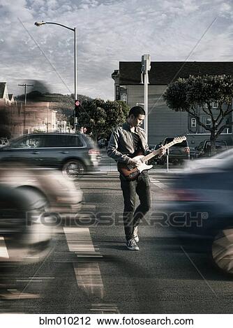 Stock Image - Thai man playing guitar in crosswalk. Fotosearch