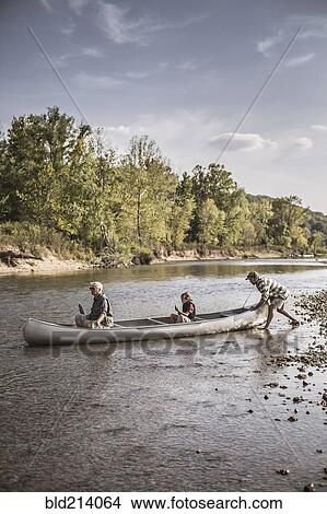Picture - Three generations of Caucasian men in canoe on river. Fotosearch