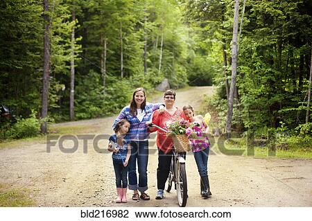 Stock Image - Three generations of Caucasian women standing on dirt road. Fotosearch
