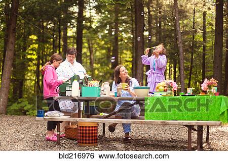 Stock Photograph - Three generations of Caucasian women cooking at picnic table. Fotosearch