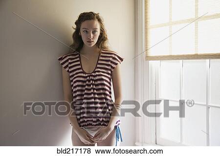 Timid woman standing near window View Large Photo Image Stock Photo - Timid woman standing near window. Fotosearch