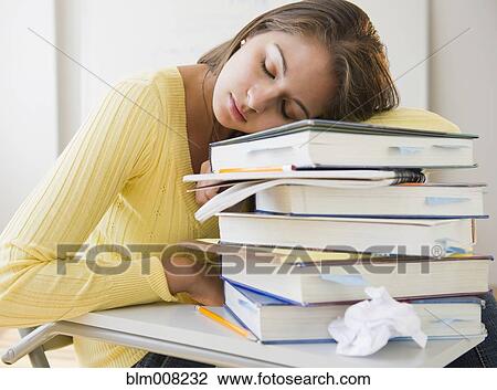 Stock Image - Tired Indian student laying on stack of textbooks. Fotosearch