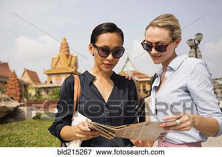 Stock Photo - Tourists reading map near temple, Phnom Penh, Cambodia. Fotosearch