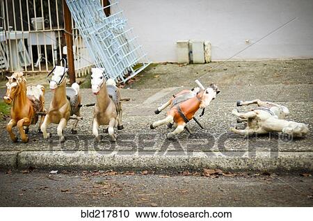 Stock Image - Toy rocking horses on city sidewalk. Fotosearch