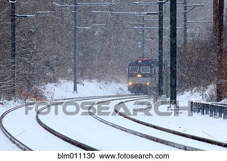 Stock Image - Train traveling on snow covered tracks. Fotosearch