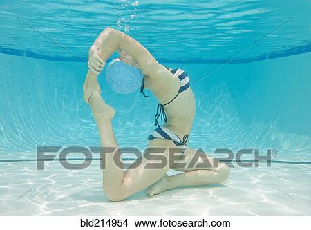 Picture - Underwater view of Caucasian woman practicing yoga in swimming pool. Fotosearch