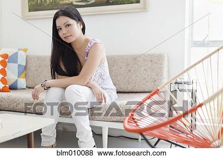Vietnamese woman sitting on sofa in living room View Large Photo Image Stock Photo - Vietnamese woman sitting on sofa in living room. Fotosearch