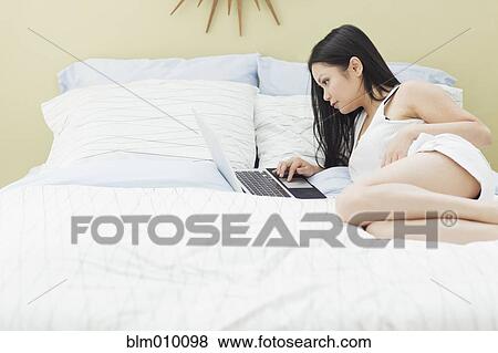 Vietnamese woman using laptop in bed View Large Photo Image Stock Photo - Vietnamese woman using laptop in bed. Fotosearch