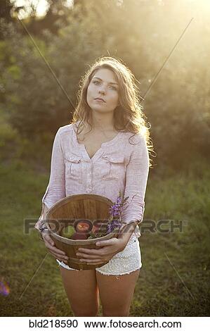 Woman carrying bucket of apples in field View Large Photo Image Stock Image - Woman carrying bucket of apples in field. Fotosearch