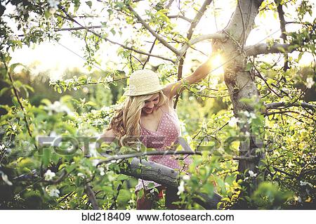 Stock Photo - Woman climbing flowering tree. Fotosearch