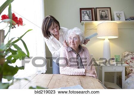 Stock Image - Woman combing hair of elderly mother. Fotosearch