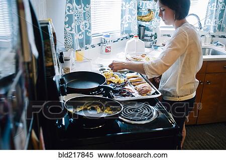Stock Photography - Woman cooking breakfast in kitchen. Fotosearch