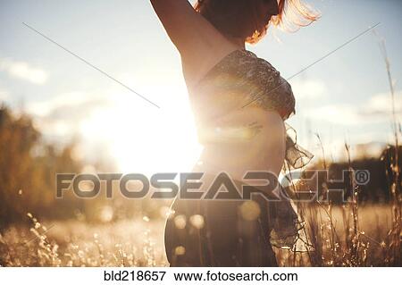 Stock Photo - Woman dancing in tall grass in rural field. Fotosearch