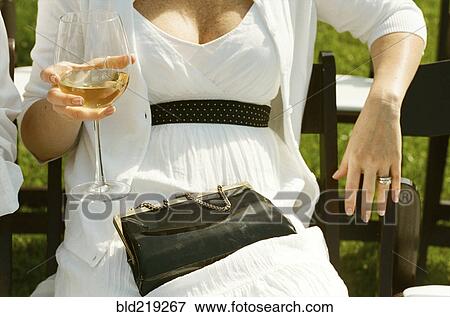 Stock Photo - Woman drinking white wine at outdoor wedding. Fotosearch