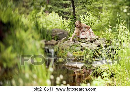 Stock Image - Woman exploring rural pond. Fotosearch