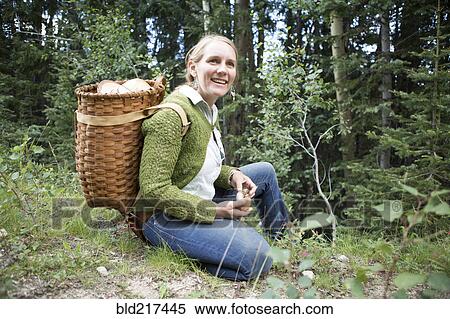 Stock Photography - Woman foraging for mushrooms in forest. Fotosearch