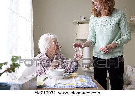 Woman giving mother glass of water View Large Photo Image Stock Image - Woman giving mother glass of water. Fotosearch