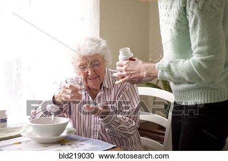 Stock Image - Woman giving mother medication. Fotosearch