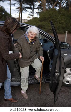 Stock Photo - Woman helping mother out of car. Fotosearch