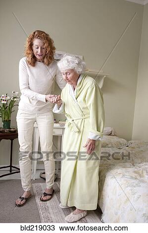 Woman helping mother walk in bedroom View Large Photo Image Stock Image - Woman helping mother walk in bedroom. Fotosearch