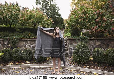 Woman holding blanket standing in courtyard View Large Photo Image Stock Photography - Woman holding blanket standing in courtyard. Fotosearch