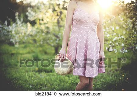 Woman holding hat in rural orchard View Large Photo Image Stock Image - Woman holding hat in rural orchard. Fotosearch