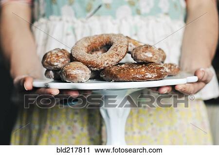 Stock Image - Woman holding plate of homemade donuts. Fotosearch