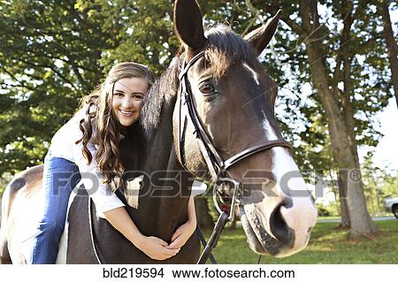 Picture - Woman hugging horse in rural field. Fotosearch