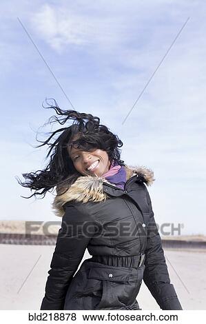 Woman in coat jumping for joy on beach View Large Photo Image Stock Photo - Woman in coat jumping for joy on beach. Fotosearch